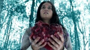 Lottie holding a bear's heart in Yellowjackets. Here are questions and theories we have about season one before Yellowjackets season 2