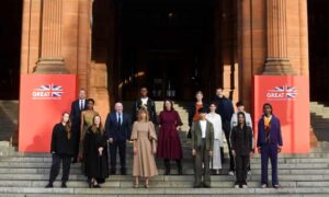 The chief executive officer of the British Fashion Council, Caroline Rush (centre), poses with models and designers on the steps outside Kelvingrove Art Gallery and Museum during a photocall for the Great Fashion for Climate Action event
