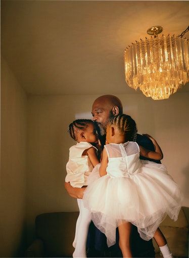 man holding two girls in white dresses