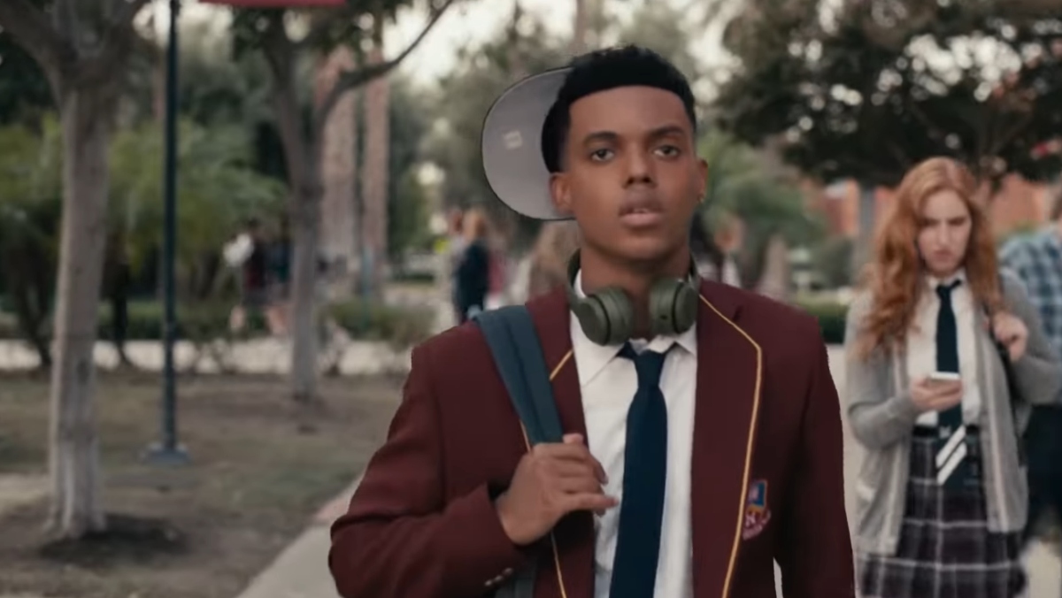 Jabari Banks as Will in Bel-Air trailer wears a burgundy suit jacket, black tie, book bag, and hat to the side