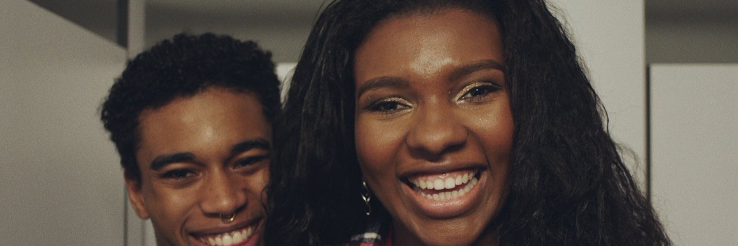 photo of a black girl with long dark hair and black guy standing behind her smiling 