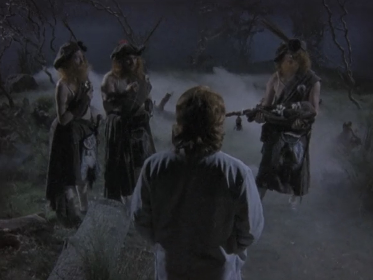 Three Scottish warriors in kilts give Rick Dagless a bagpipe on Garth Marenghi's Darkplace