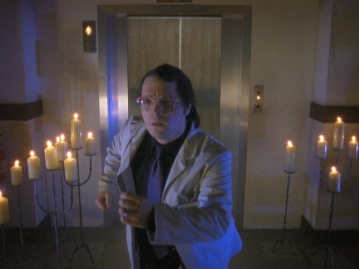 Matthew Holness runs out of an elevator past candles on Garth Marneghi's Darkplace