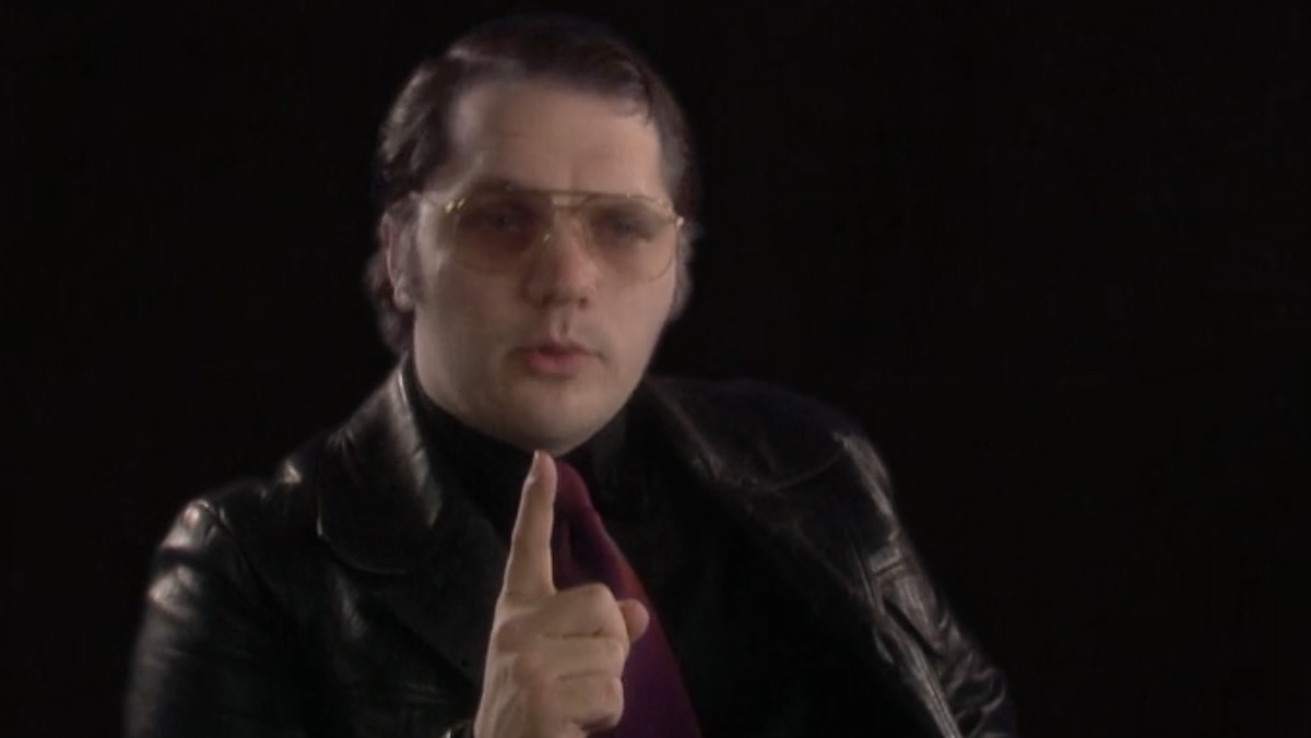 Matthew Holness points his finger up as Garth Marenghi