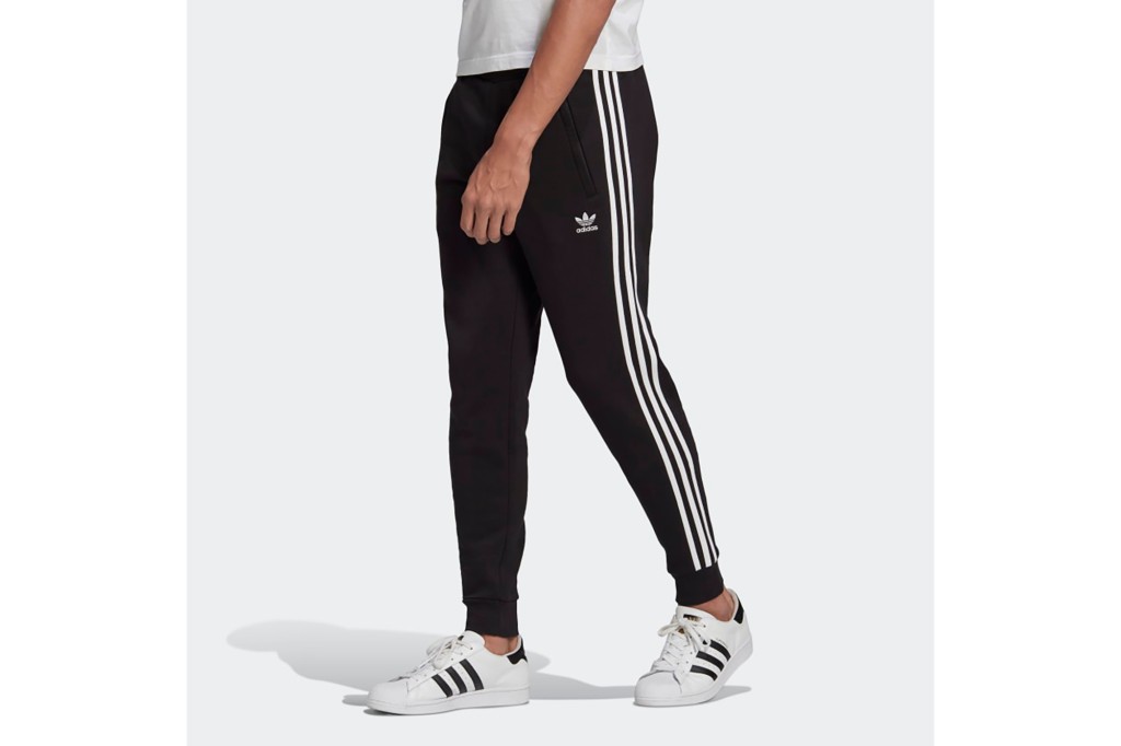 A man's lower body in black Adidas track pants 
