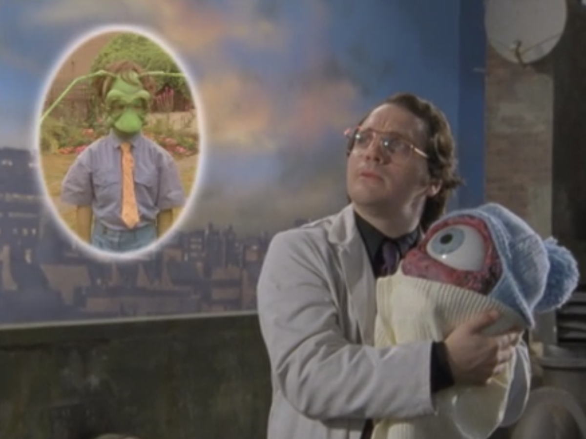 Dr, Rick Dagless holds the eyechild and looks up at his grasshopper son Skipper on Garth Marenghi's Darkplace 