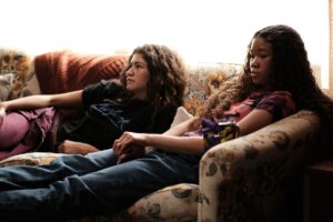 Rue and Gia sitting together on a sofa, in HBO Max’s Euphoria.