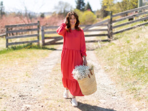 Jillian Harris wearing a red dress in a field to illustrate an article about Joe Fresh x Jillian Harris collection 2021.