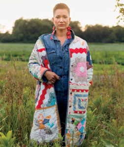 Olympian Waneek Horn-Miller wearing a patchwork coat in a field.