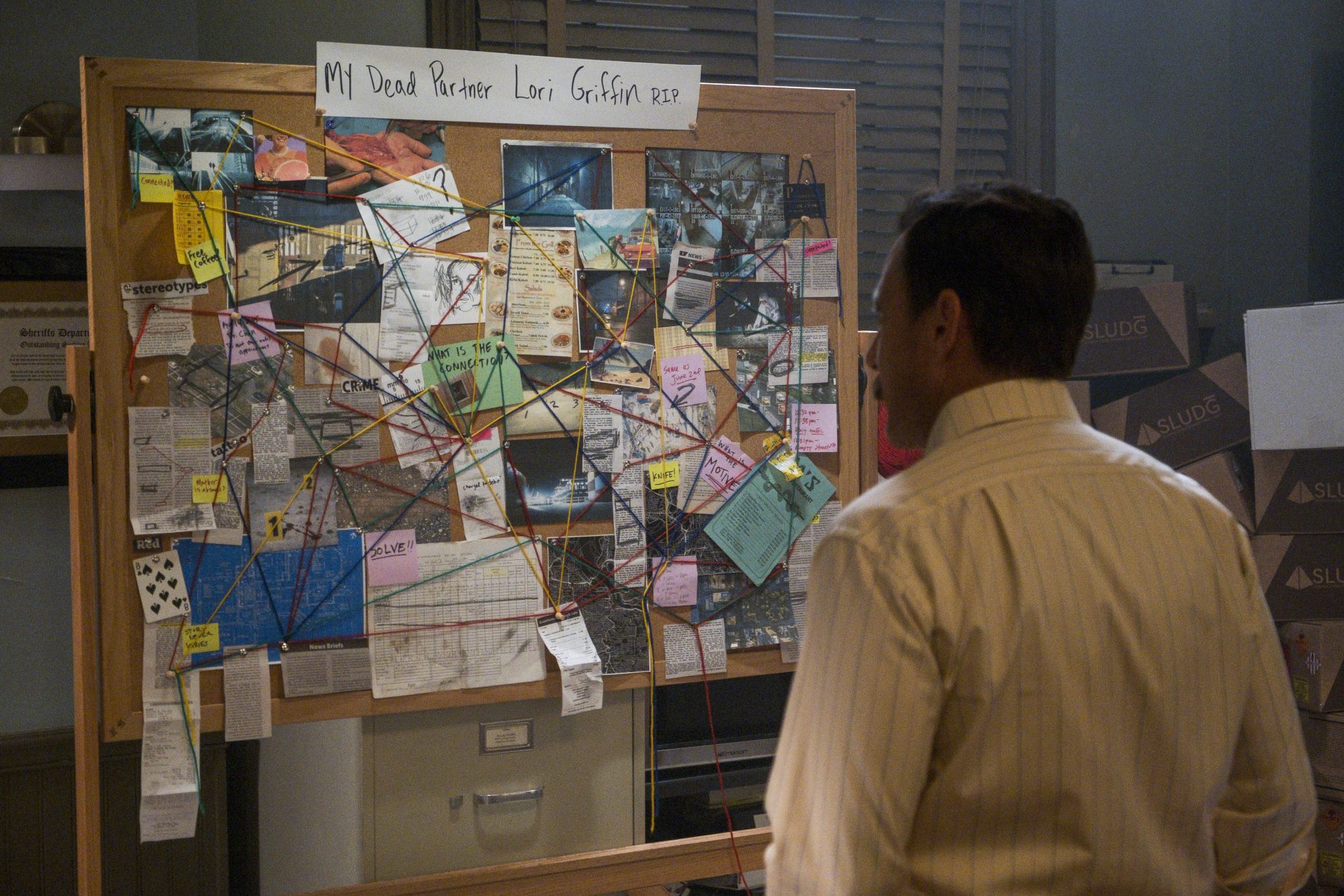 MURDERVILLE_Will Arnett in front of a theory board
