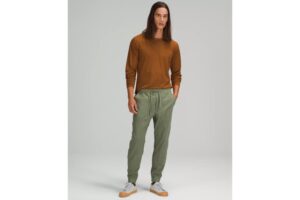 A man in a burnt orange sweater and olive green jogger pants