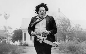 Leatherface, chainsaw in hand, running down the road in the 1974 original Texas Chain Saw Massacre