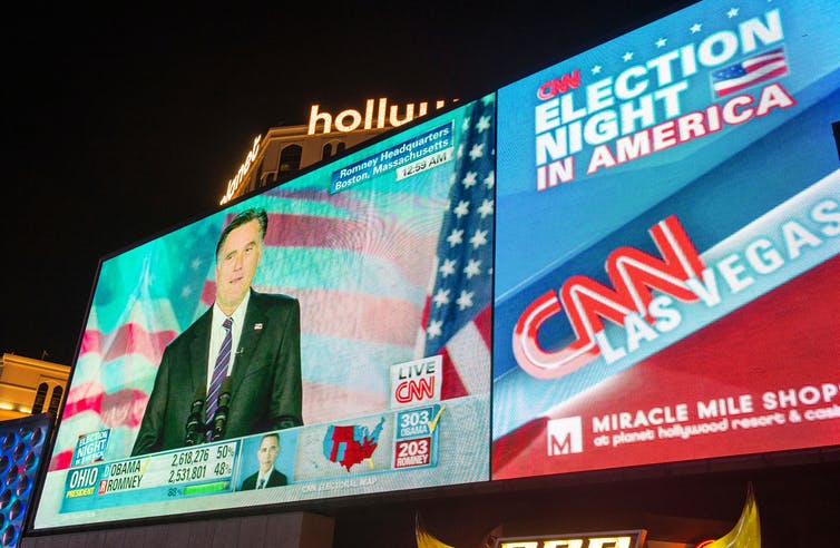 An outdoor screen featuring live coverage of the 2012 US election results.