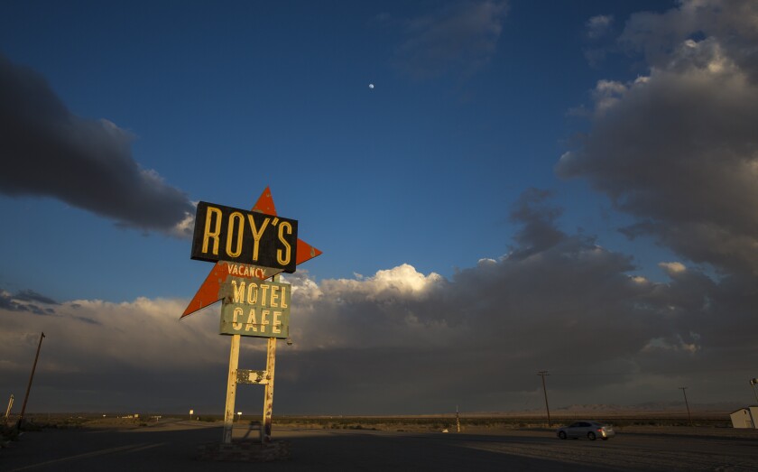 A large sign on a highway that reads 'Roy's vacancy motel cafe'