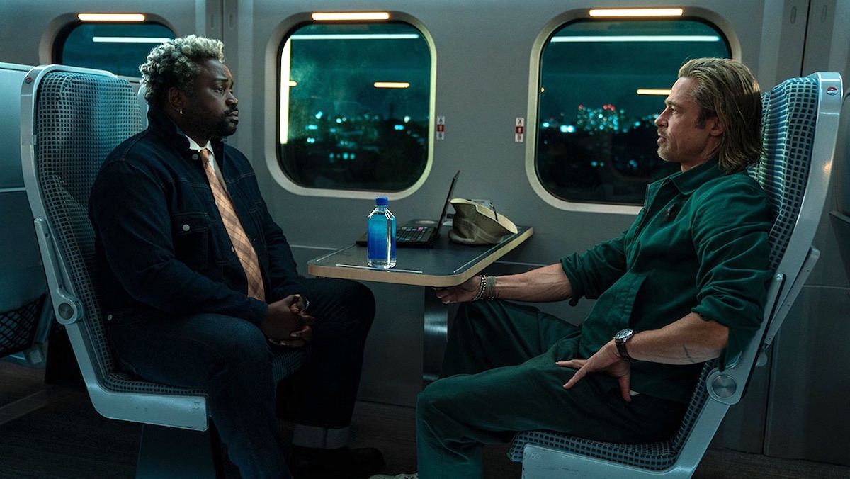 Brian Tyree Henry and Brad Pitt sit opposite each other on a train in Bullet Train's trailer
