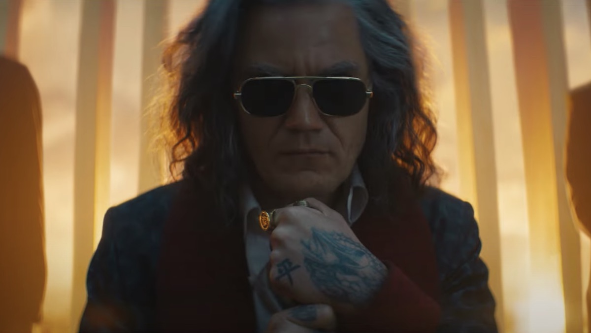 A long-haired Michael Shannon with sunglasses rests against a cane in Bullet Train
