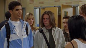 Drake as Jimmy on Degrassi stands in hallway with other teens Degrassi reboot