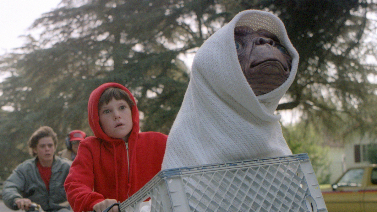 Elliott rides his bike with E.T. in the front basket