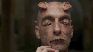 photo of a man with his eyes and mouth sewn shut and extra ears on his forehead david cronenberg crimes of the future trailer