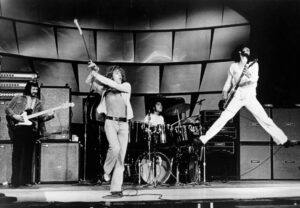 A black-and-white photo of a four-man band playing onstage in the 1970s