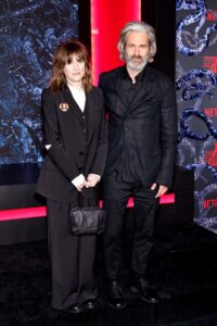 Winona Ryder and Scott Mackinlay Hahn, both dressed in black slacks and suit jackets, attend Netflix