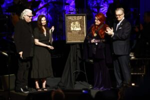 Wynonna Judd, second from the right, stands next to the Judds' induction plaque as sister Ashley Judd, left, Ricky Skaggs, and MC Kyle Young, CEO of the Country Music Hall of Fame & Museum look on during the Medallion Ceremony at the Country Music Hall of Fame.