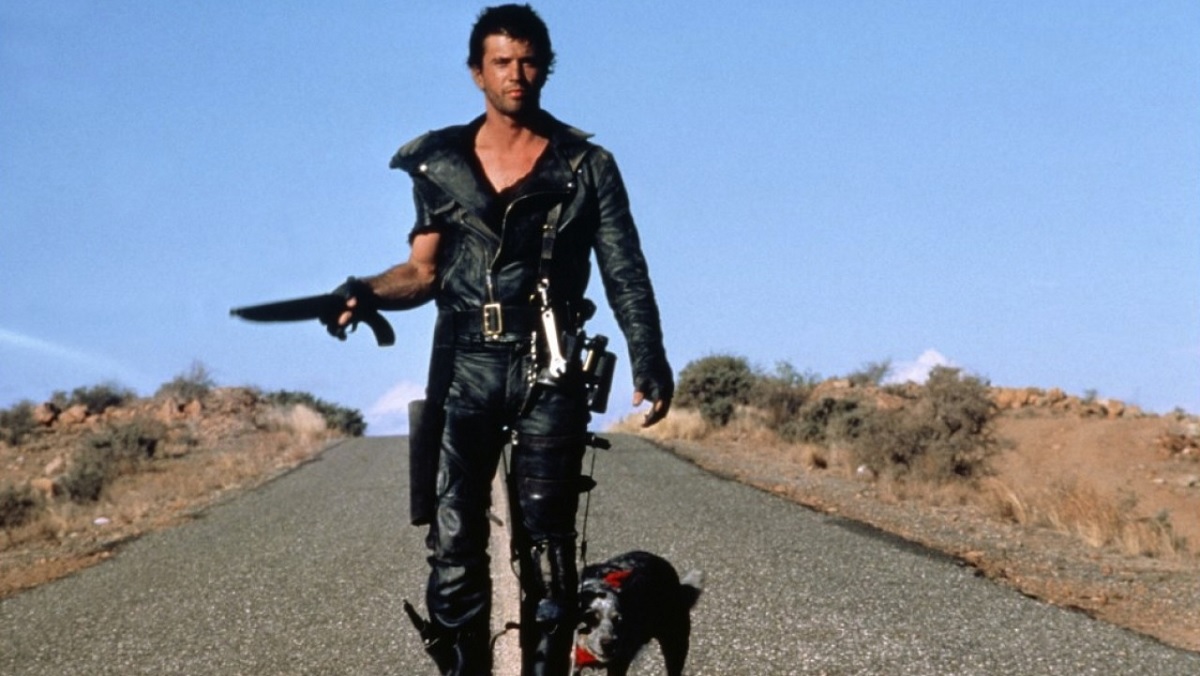 Max (Mel Gibson) walks down the middle of the road with his dog in The Road Warrior.
