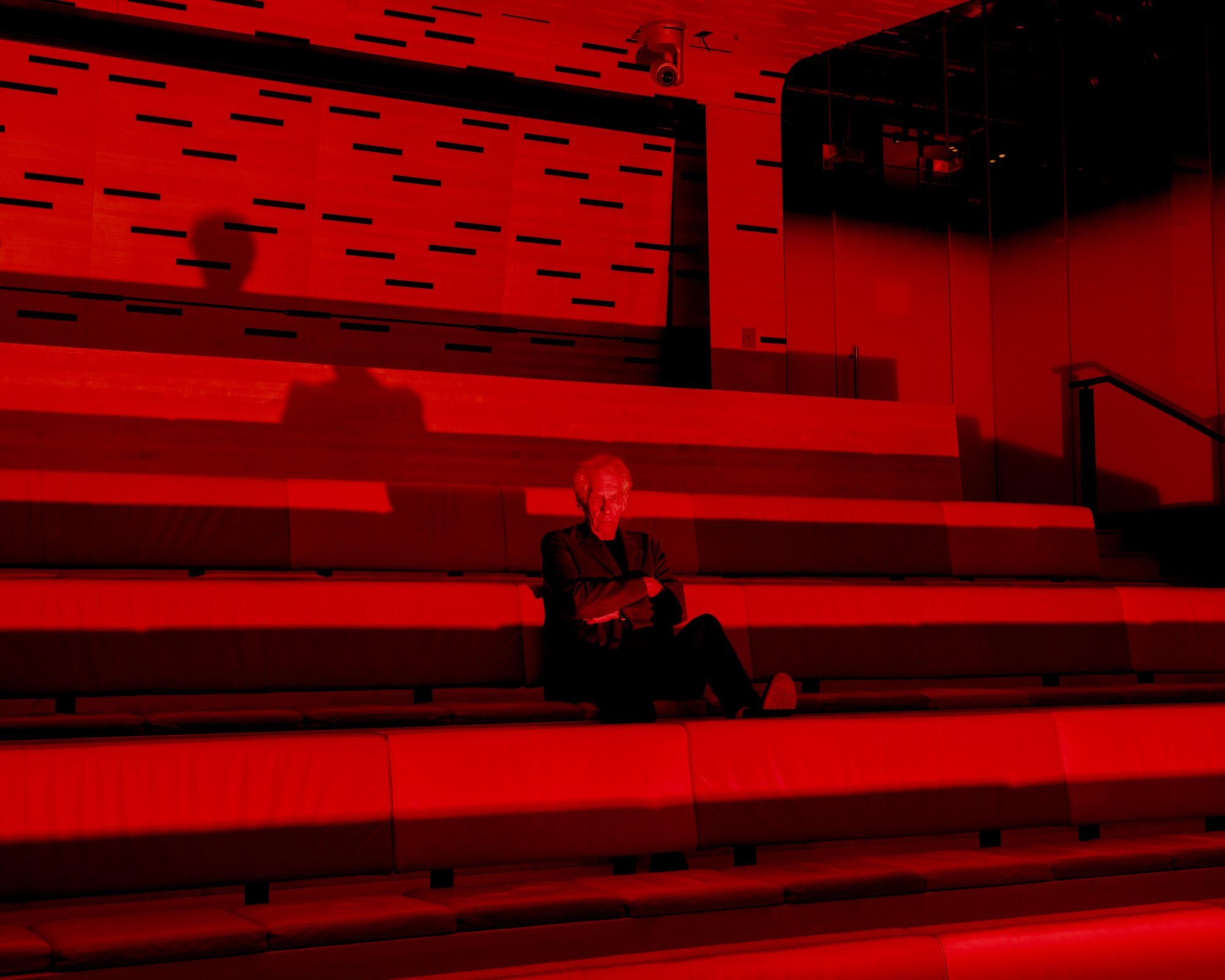 A man sits on stadium-style seats under red lighting