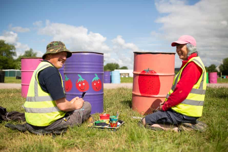 Simon and Debbie Lodge, residents of Pilton village, paint fruity designs on bins in the market field