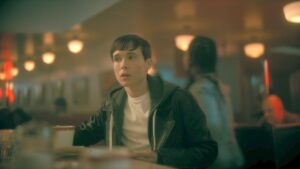 photo of Viktor Hargreeves in Umbrella Academy sitting at a bar wearing a dark jacket and white shirt