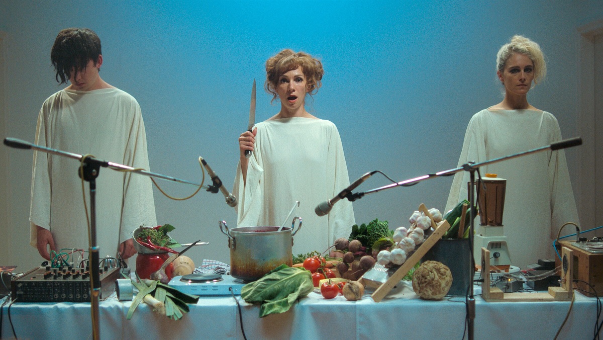Asa Butterfield, Fatma Mohamed, and Ariane Labed swear smocks and begin their odd sonic catering art performance in Flux Gourmet.