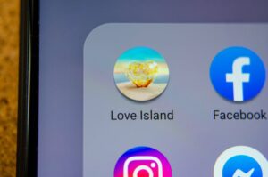 A close up image of the Love Island app icon alongside other apps on a smartphone