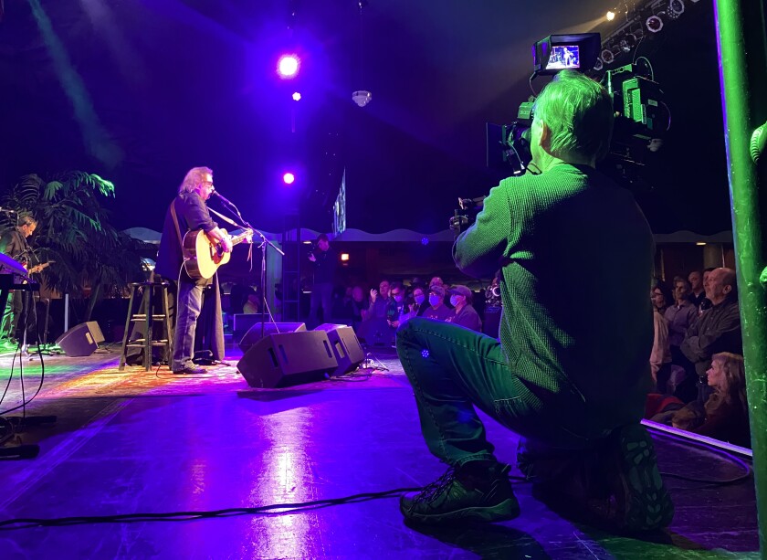 A cameraman records a musician onstage with a guitar on the set of the documentary "The Day the Music Died."