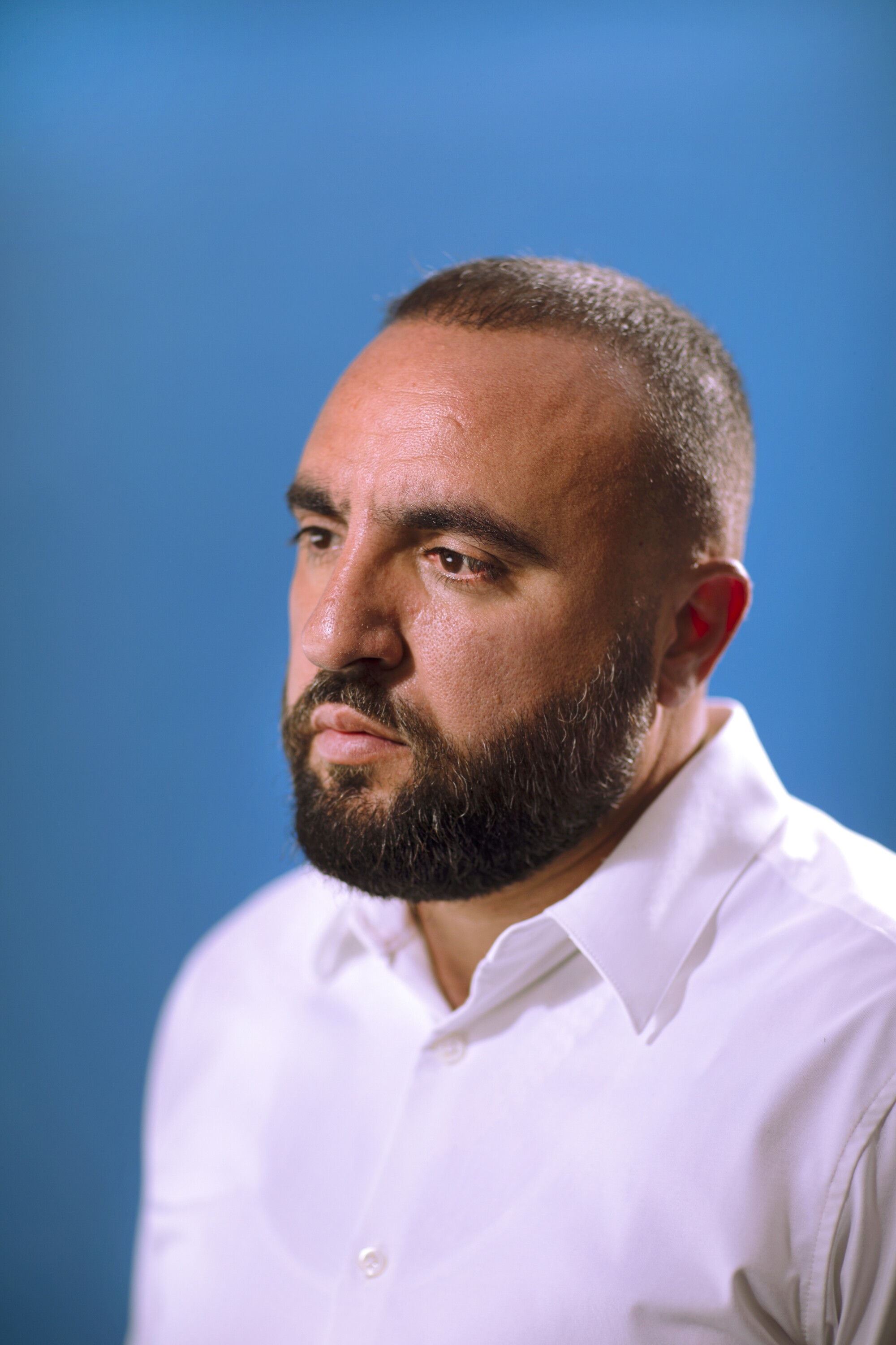 A man with a beard in blue white shirt on a blue background