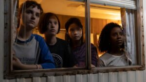 photo of four paper girls standing inside a trailer looking outward