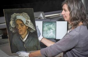 Senior Conservator Lesley Stevenson views "Head of a Peasant Woman" alongside an x ray image of the hidden Van Gogh self portrait.