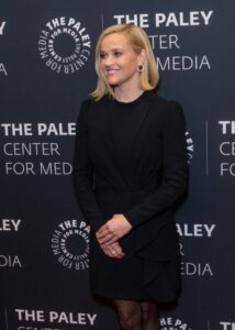 Reese Witherspoon smiles in all-black dress with black stockings