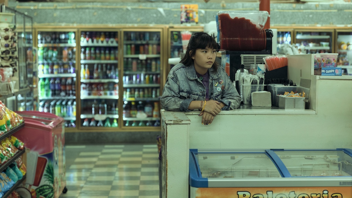 Young Erin stands behind a shelf in a convenience store on Paper Girls