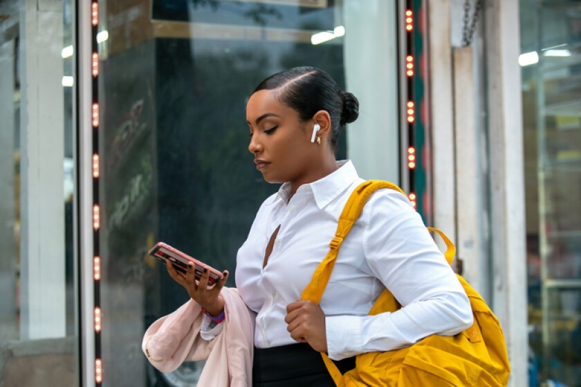 A woman walking down the street looking at her phone