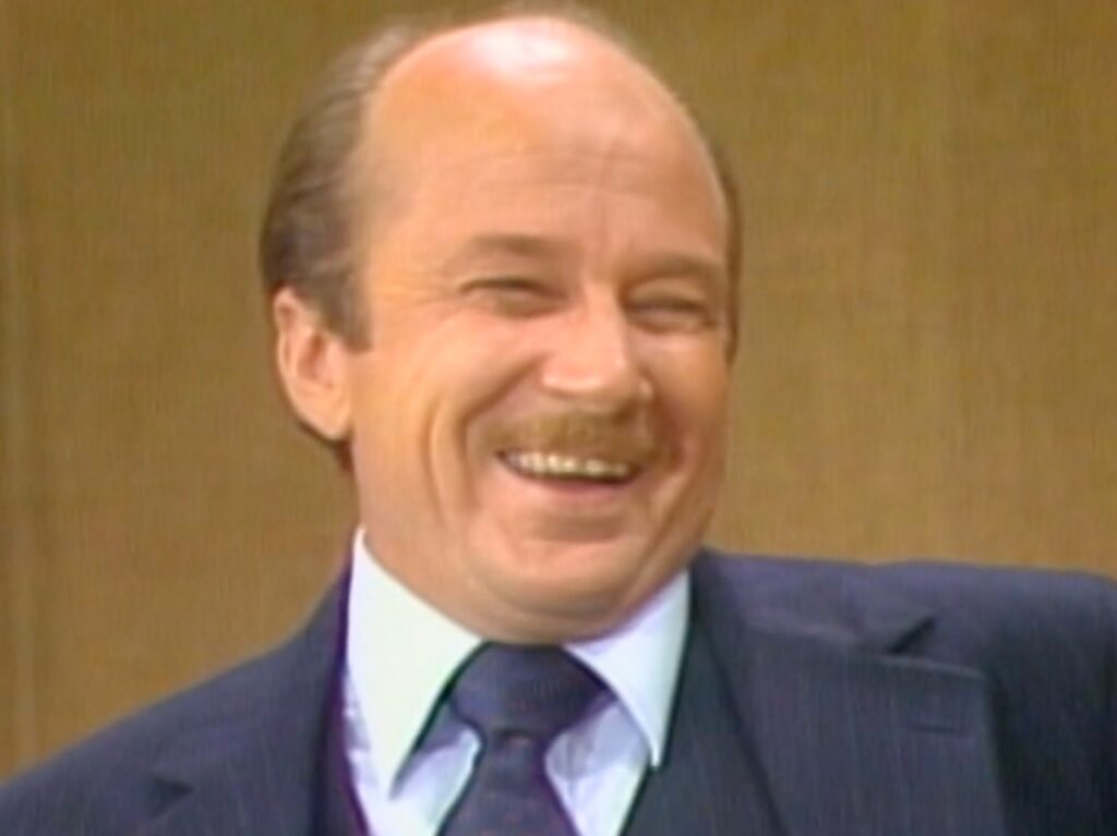 Actor Macom McCalman appearing in "Three's Company" smiling with blue suit and tie on