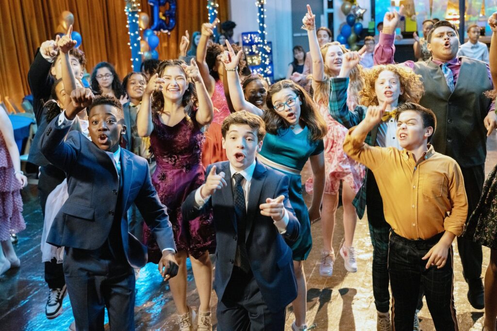 13: THE MUSICAL, (aka THIRTEEN: THE MUSICAL), Ramon Reed (front left), Frankie McNellis (purple dress), Eli Golden (front center), Shechinah Mpumlwana (center, rear), Gabriella Uhl (blue dress), Khiyla Aynne (center right, print dress), Savino Quatela (front right), Luke Islam (right, print tie), 2022. ph: Alan Markfield /  Netflix / courtesy Everett Collection