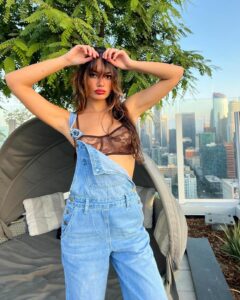 Kayla Carter strikes a pose in a brown bra and overalls