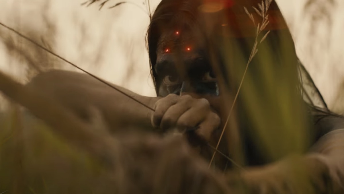 Three red dots sit on the forehead of a Comanche Nation warrior aiming a bow and arrow in the Predator prequel Prey from Hulu
