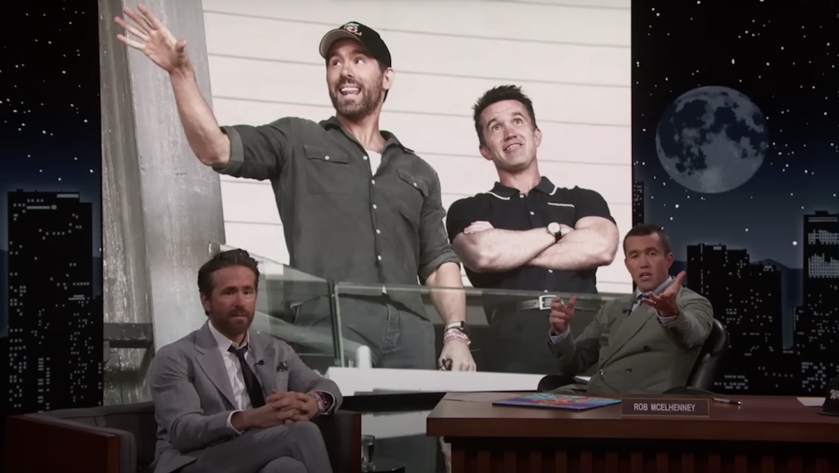 Ryan Reynolds a guest on Jimmy Kimmel and guest host Rob McElhenney sit in front of a giant picture of the two of them standing
