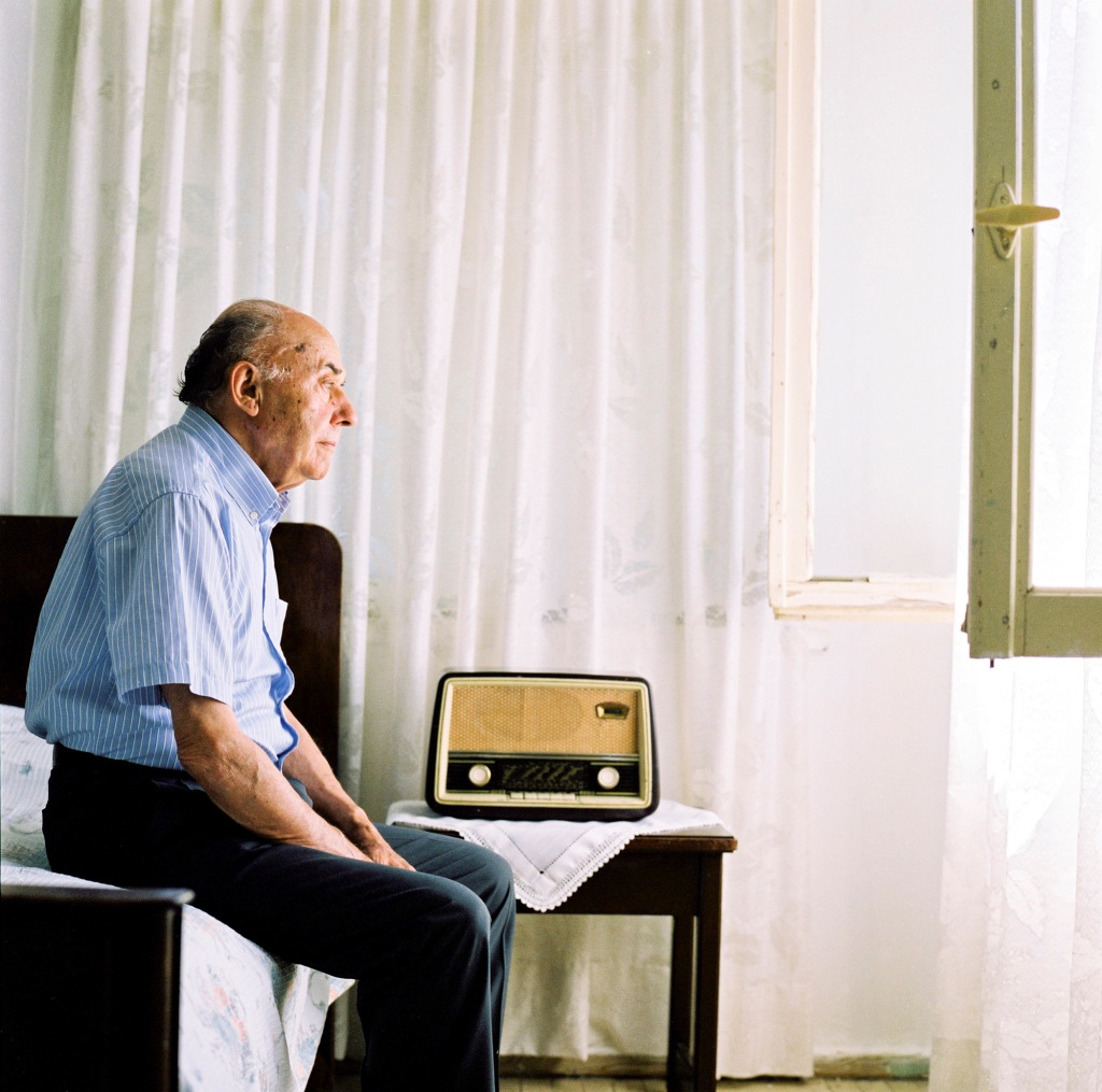 An older man sitting by a radio