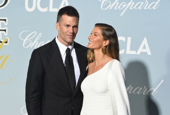 Tom Brady and Gisele Bündchen arrive at the 2019 Hollywood For Science Gala/ Bündchen is wearing a one shoulder white dress and Brady is wearing a classic black suit and tie