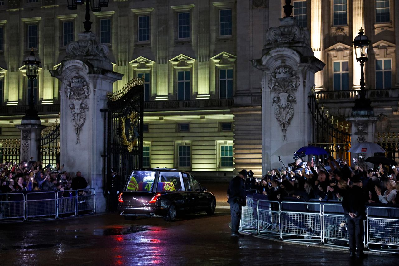 The hearse carrying the flag-draped casket of Queen Elizabeth II enters the center gate at Buckingham Palace.