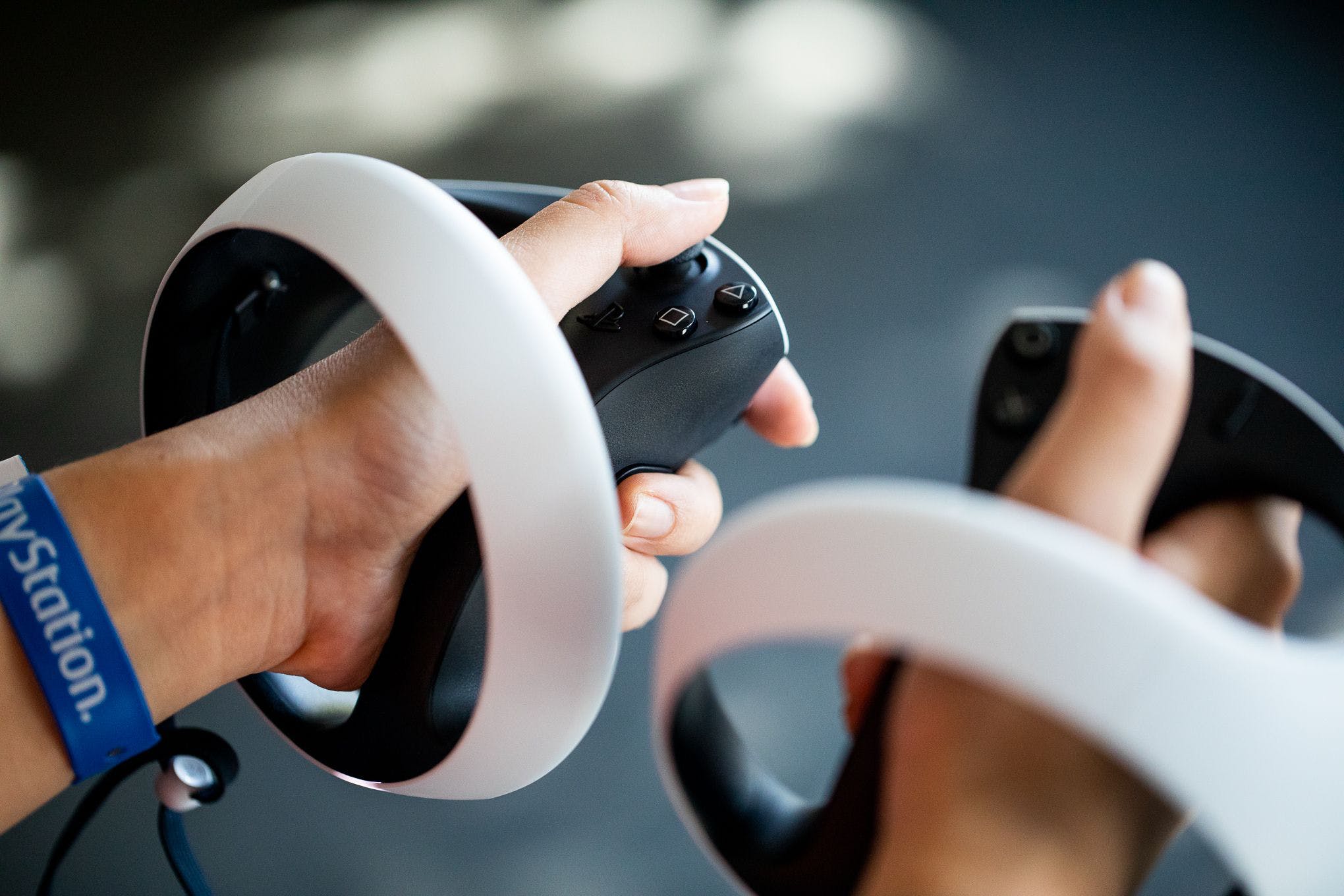 A person holds the left and right PSVR2 sense controllers in their hands.