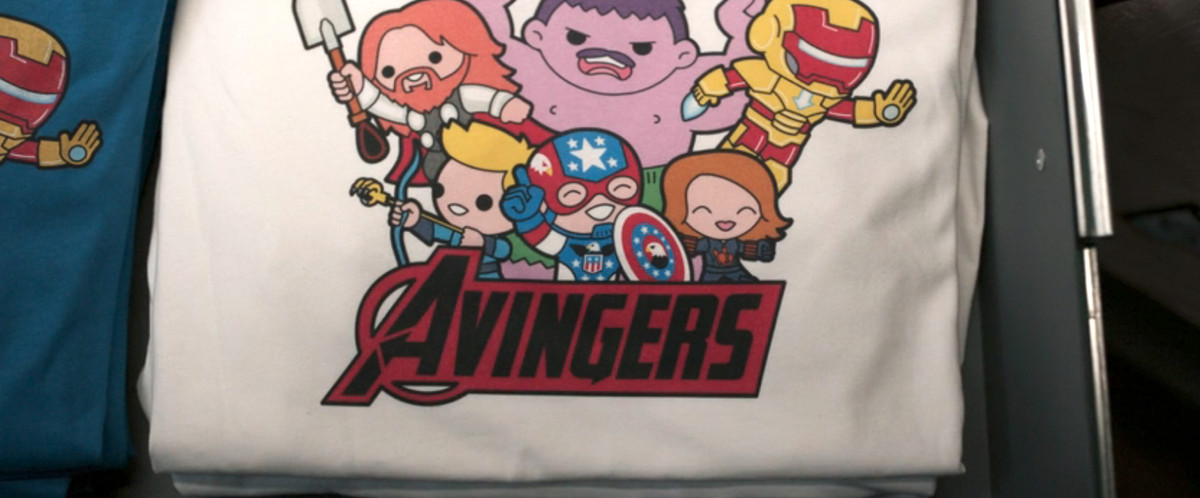 a white t-shirt featuring chibi designs of the avengers characters, but all slightly off. the hulk is purple, thor has red hair, and below it says Avingers