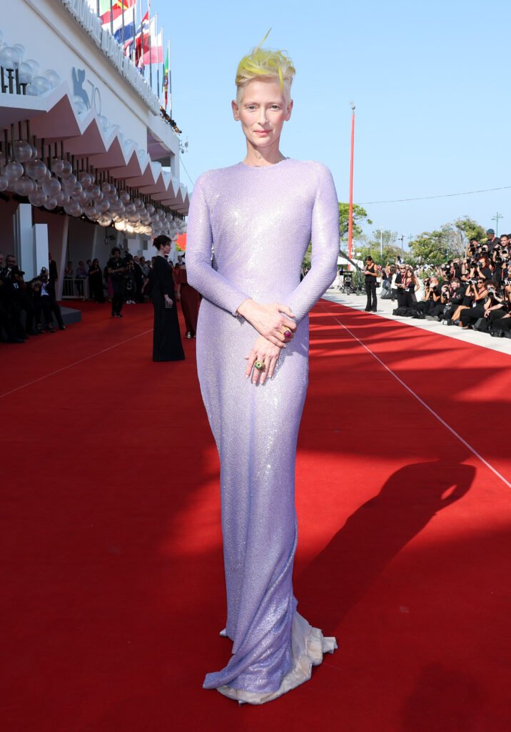 Tilda Swinton poses in longsleeved lavender dress with shimmers
